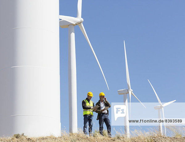 Arbeiter im Gespräch mit Windkraftanlagen in der ländlichen Landschaft