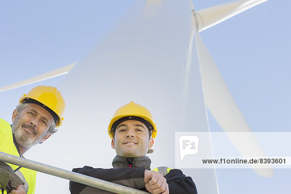 Arbeiter  die auf einer Windkraftanlage in ländlicher Landschaft stehen