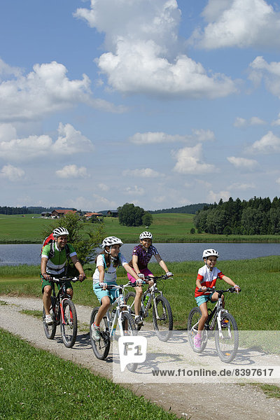 Family on a bicycle tour  in Seeweiler  Seeg Ostallgaeu  Swabia  Bavaria  Germany