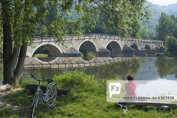 Restaurierte Saalebrücke  Radfahrerin sitzt am Ufer  Jena-Burgau  Jena  Thüringen  Deutschland