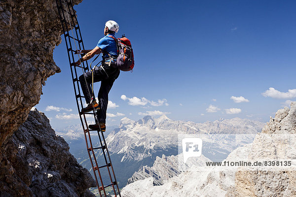 Bergsteiger beim Aufstieg über die Via ferrata Marino Bianchi auf den Cristallo di Mezz  hinten die Tofane  Dolomiten  Belluno  Italien