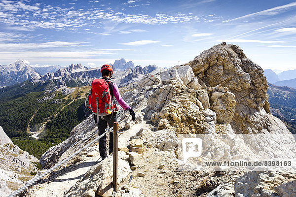 Mountain climber descending from Lagazuoi Mountain in the Fanes Group  in front of Pelmo Mountain  Dolomites  Belluno  Italy