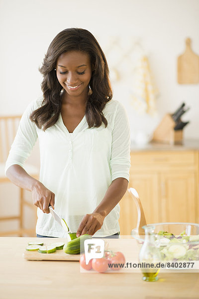 Black woman chopping vegetables in kitchen