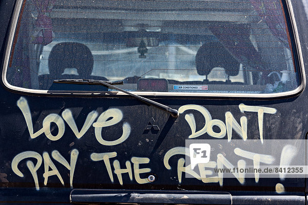 '''Love don't pay the rent''  written on the rear of a motor vehicle  Augusta  Western Australia  Australia'