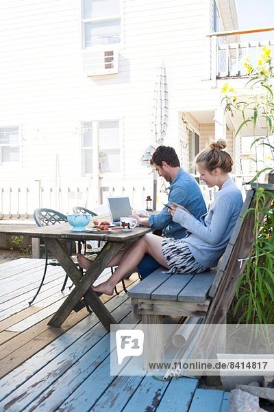 Couple on patio with laptop and mobile  Breezy Point  Queens  New York  USA
