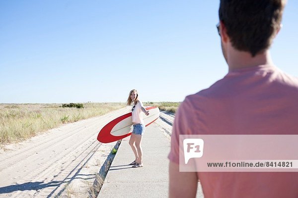 Couple with surfboard on coastal path  Breezy Point  Queens  New York  USA