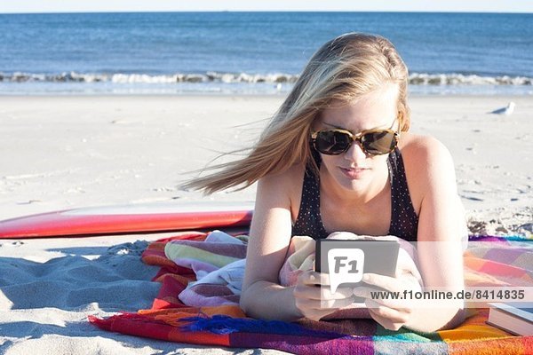 Junge Frau beim Betrachten des digitalen Tabletts am Strand  Breezy Point  Queens  New York  USA