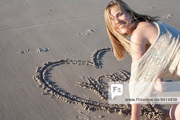 Lächelnde Frau schreibt Liebesbotschaft in Sand  Breezy Point  Queens  New York  USA