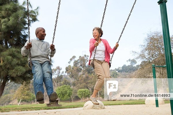 Senior couple on swings in park