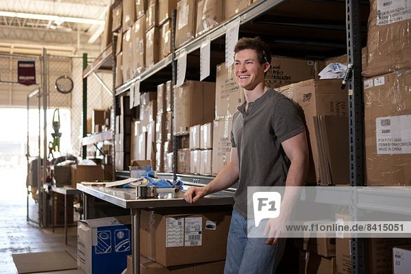 Worker standing in warehouse  leaning against shelving