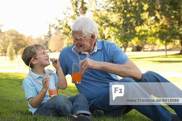 Grandfather and grandson drinking through straw eyeglasses