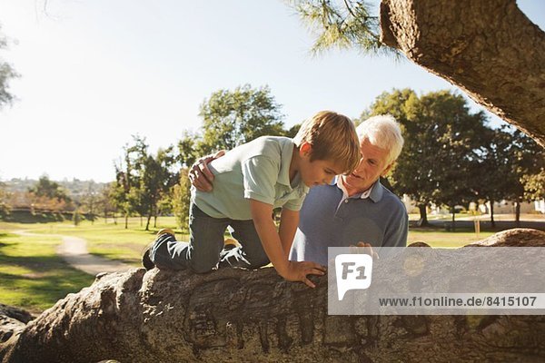 Großvater hilft Enkel beim Baumklettern