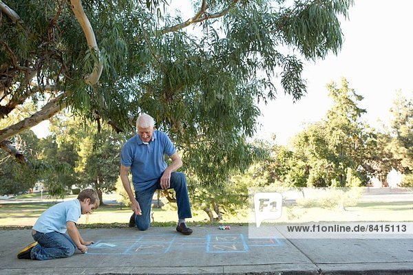 Grandfather and grandson drawing hopscotch