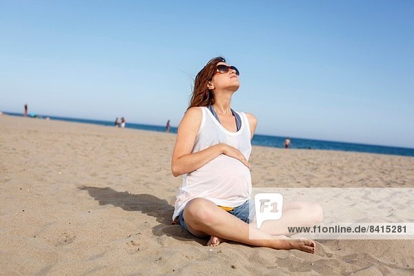 Pregnant woman sitting on beach