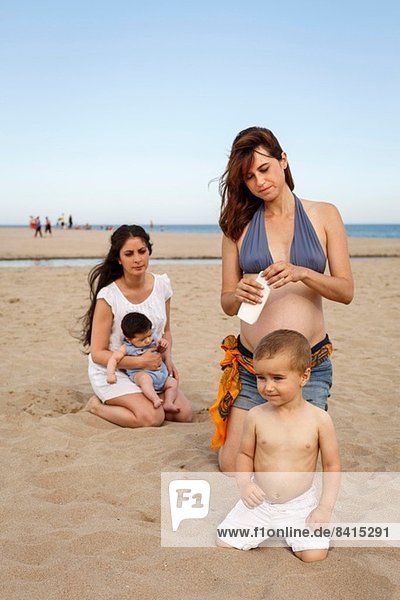 Mütter und Babys am Strand  Mutter hält eine Flasche Sonnencreme