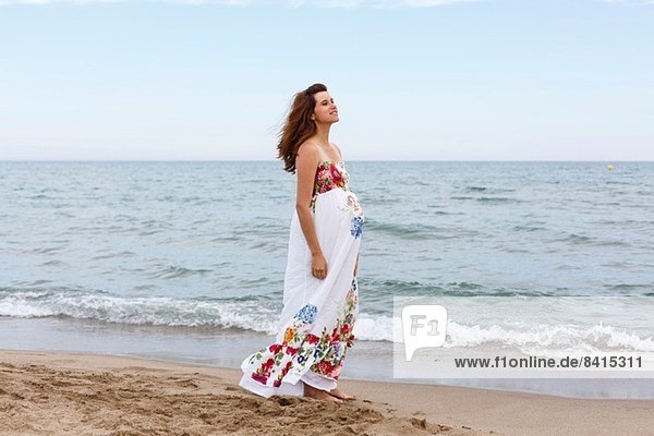 Pregnant woman walking along beach