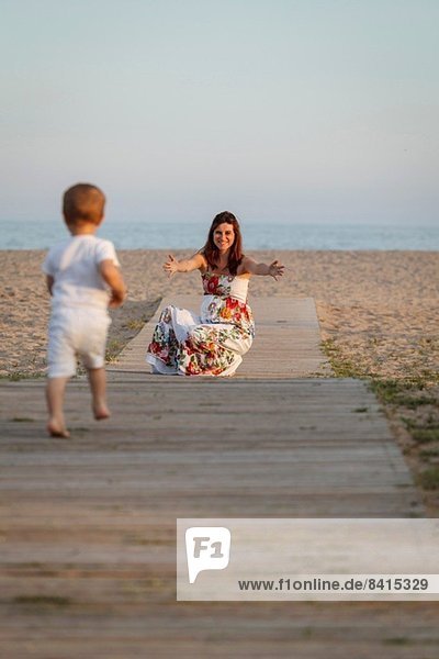 Kleinkind rennt zur Mutter auf der Promenade