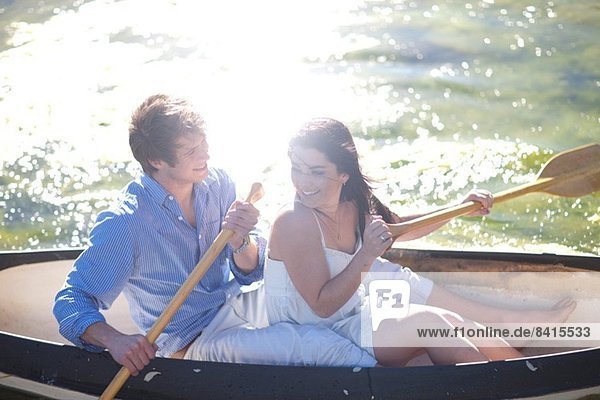 Young couple in rowing boat on river in sunlight