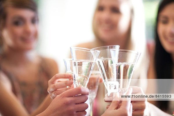 Gruppe weiblicher Freunde  die mit einem Glas Champagner anstoßen.