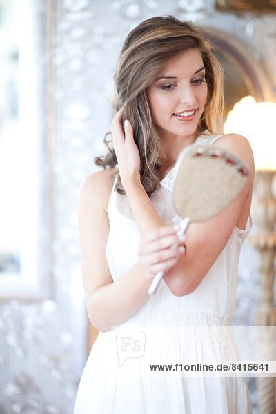 Porträt einer jungen Frau mit Blick in den Handspiegel