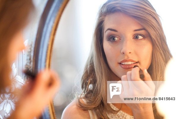 Junge Frau mit Lippenstift im Spiegel