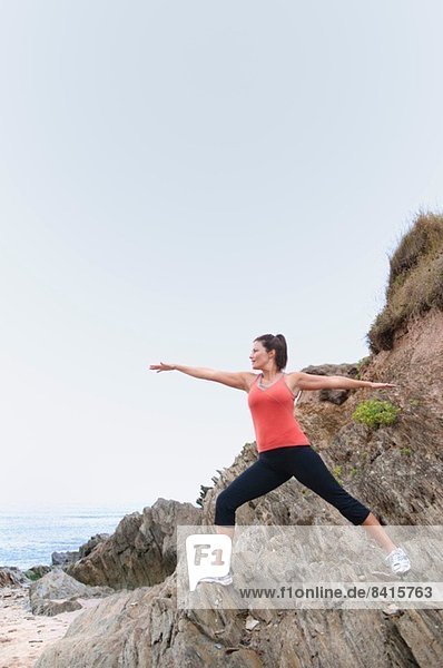 Mature woman exercising on rocks