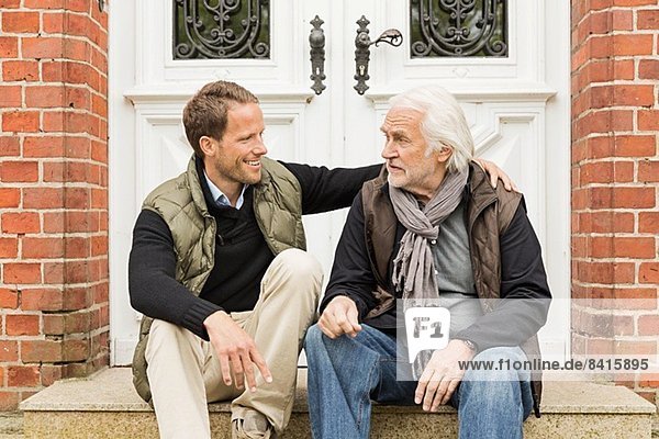 Vater und Sohn sitzen vor der Haustür