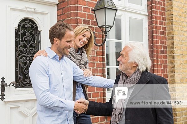 Mittleres erwachsenes Paar vor der Haustür  älterer Mann mit Händeschütteln