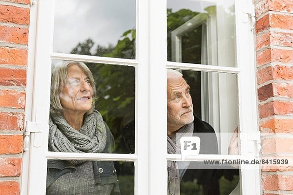 Seniorenpaar schaut durchs Fenster