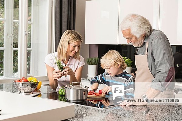 Drei Generationen Familie bei der Zubereitung von Speisen