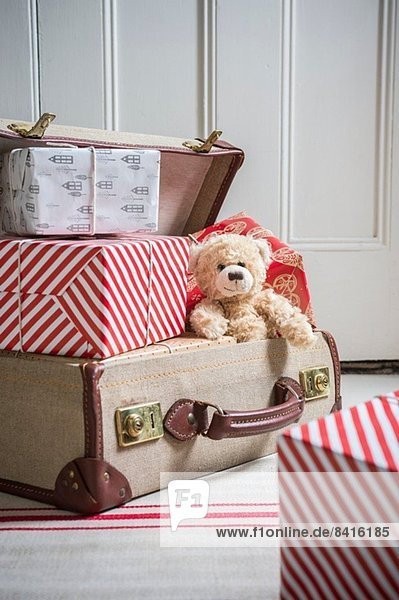 Koffer gefüllt mit verpackten Geschenken und Teddybär
