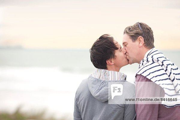 Schwules Paar küsst sich am Strand
