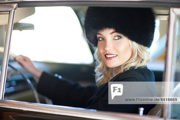Woman with fur hat driving vintage car