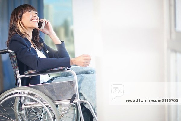 Woman in wheelchair using mobile phone