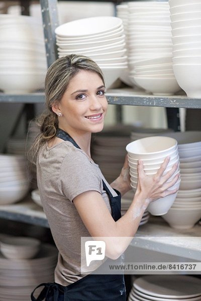 Potter stacking bowls onto shelf at crockery factory