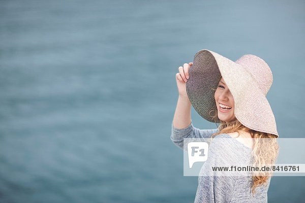Frau mit Hut genießt das Meer