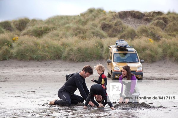 Familie mit zwei Jungen  die am Strand spielen