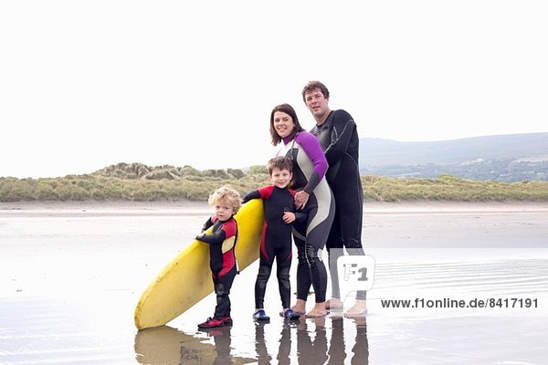 Family with two boys and surfboard on beach