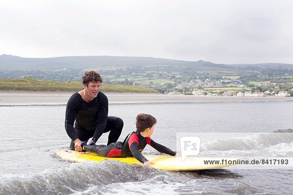 Vater bringt dem Sohn das Surfen bei