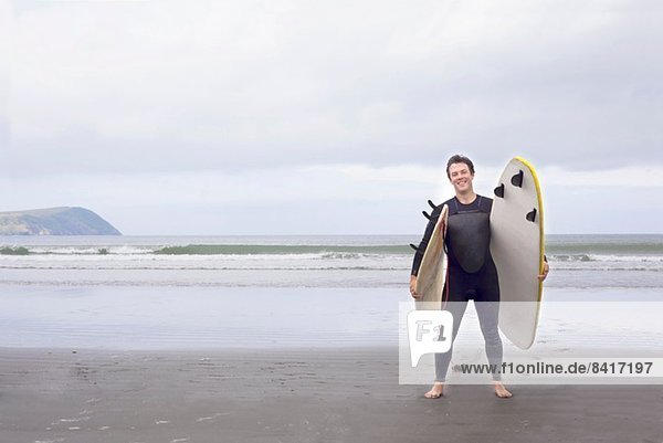 Porträt eines Mannes mit Surfbrettern am Strand