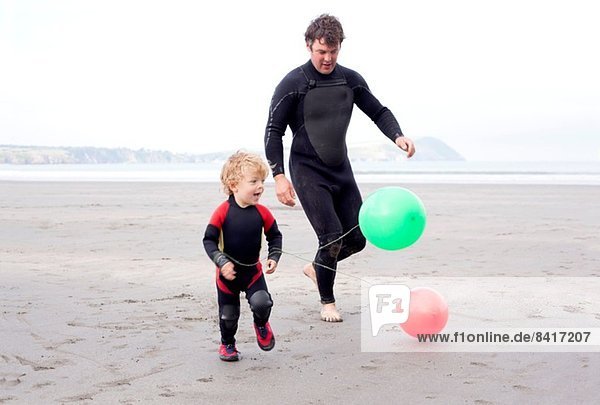 Vater und Sohn spielen mit Luftballons am Strand