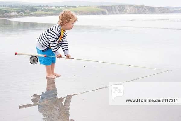 Junge am Strand stehend mit Angelrute