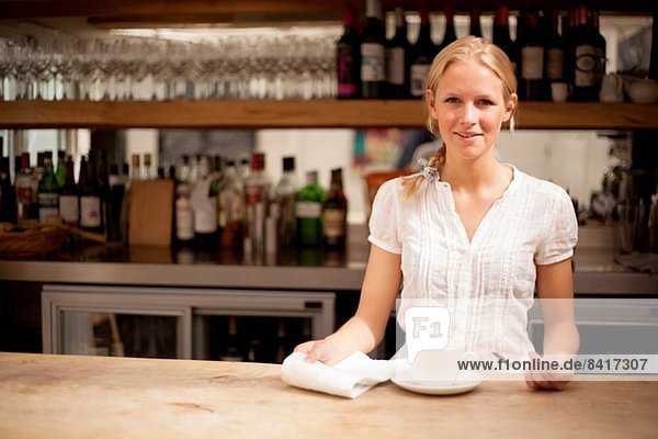 Portrait of young waitress behind coffee bar counter