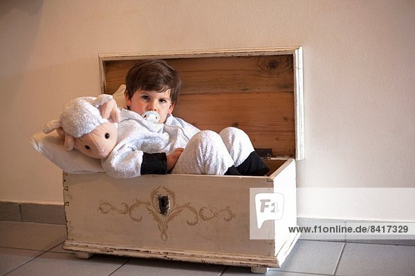 Porträt eines männlichen Kleinkindes in einem kleinen Holzkoffer
