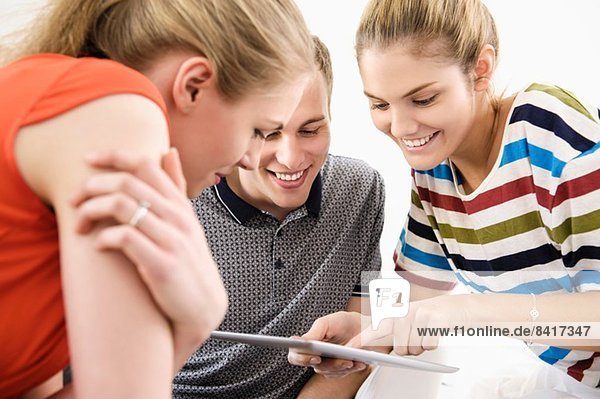 Drei junge erwachsene Freunde mit digitalem Tablett