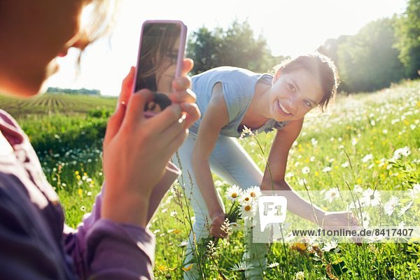 Mädchen beim Fotografieren von Mädchen beim Blumenpflücken