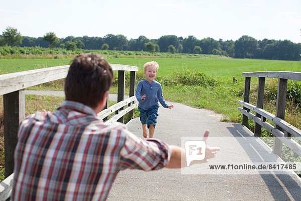 Junge rennt über Holzbrücke auf Papa zu