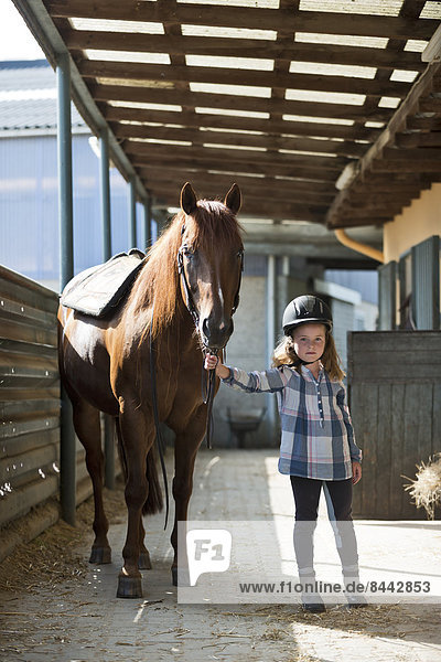 Little girl with horse in stable