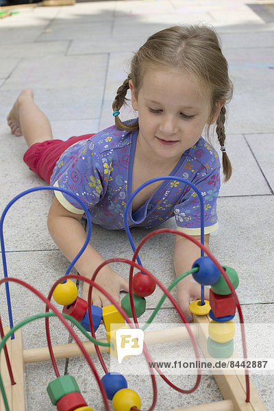 Little girl playing with coloured wooden toy