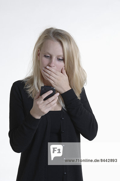Schockierte junge Frau beim Anblick des Smartphones